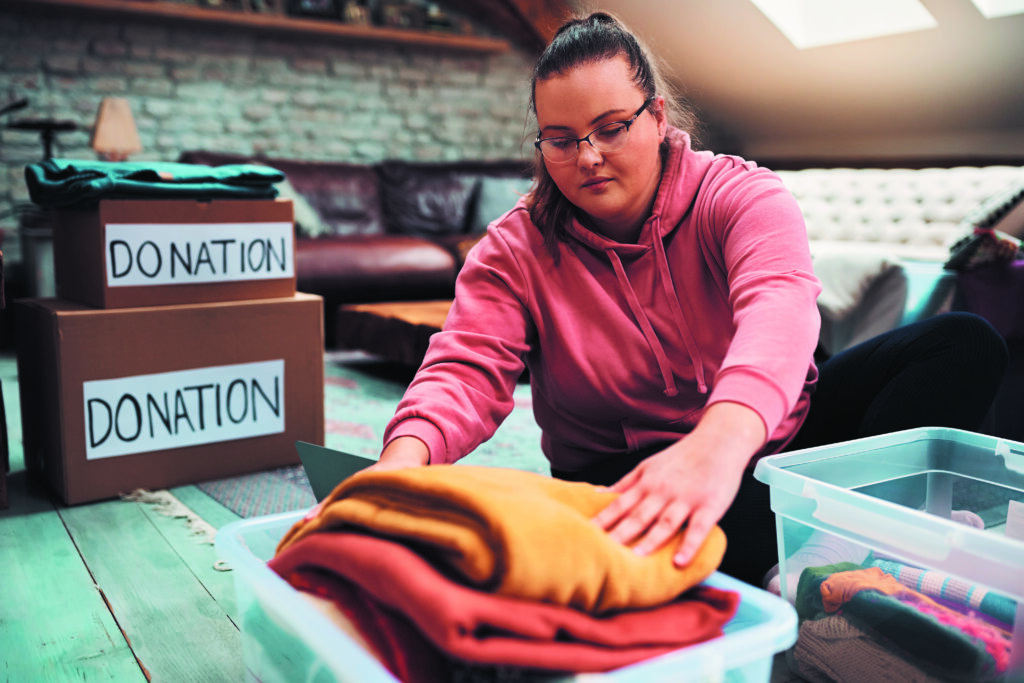 Close-up of woman sorting clothes while packing donation boxes for charity.